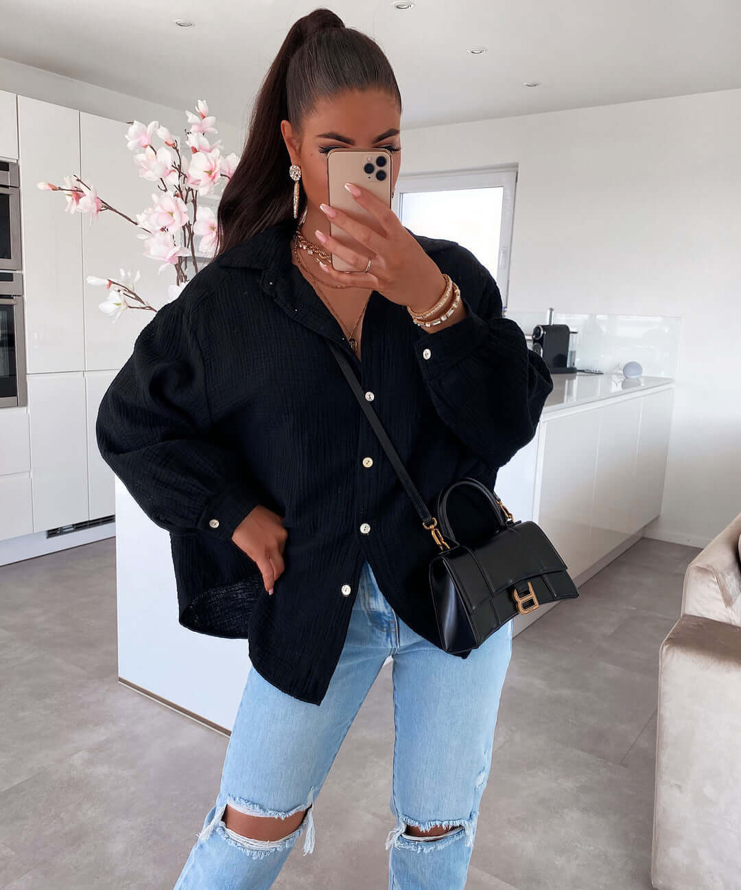 Chemise élégante noire avec coupe ajustée, portée avec un sac noir et jeans, idéal pour un look décontracté.